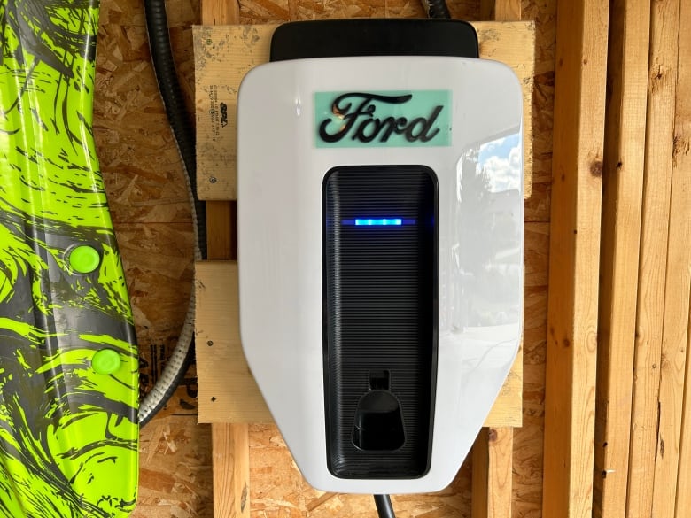 A white box which reads Ford is mounted on a wooden wall in a garage.