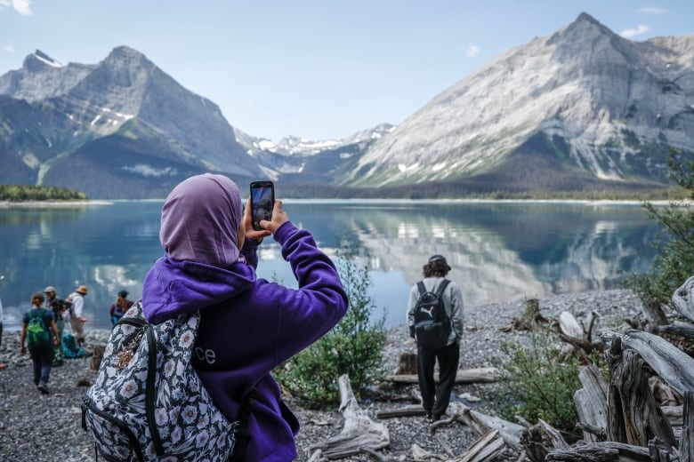 Eesha Haris, left, uses her phone to photograph Upper Kananaskis Lake while attending the Rockies Journey camp run by Howl in Kananaskis, Monday, July 3, 2023.