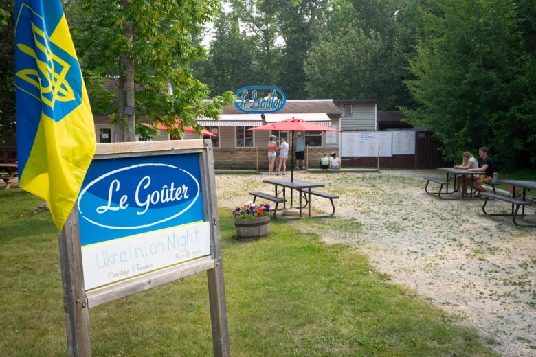 A sign that says Le Goûter stands in front of a restaurant.