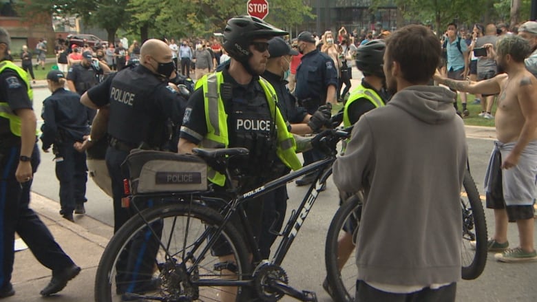 A Halifax Regional Police officer with a bicycle lifts it off the ground using the "chest push" technique for moving people back. 