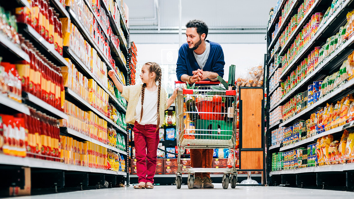 father and daughter with trolley in supermarket aisle