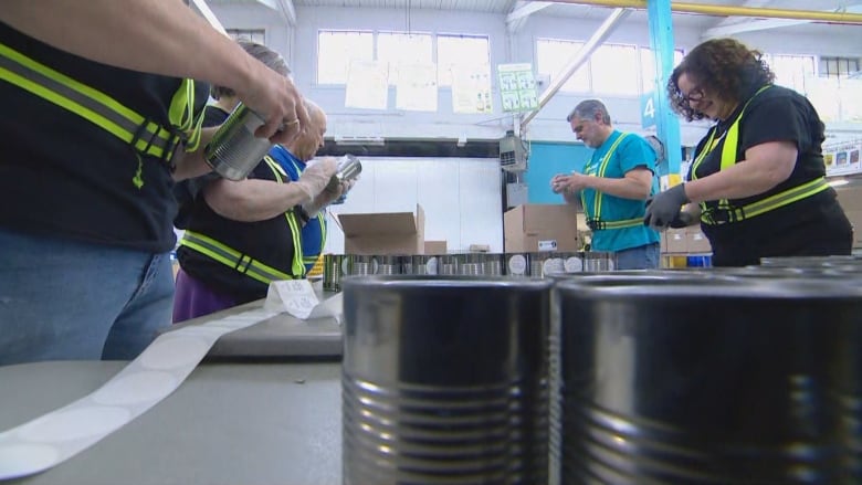 Volunteers work to package cans at a food bank.