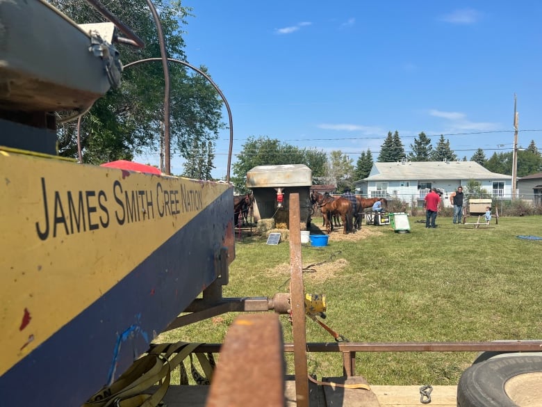 A chuckwagon with "James Smith Cree Nation" painted on the side sits in the foreground. Darryl Burns and his family are in the background, setting up horses for upcoming races.