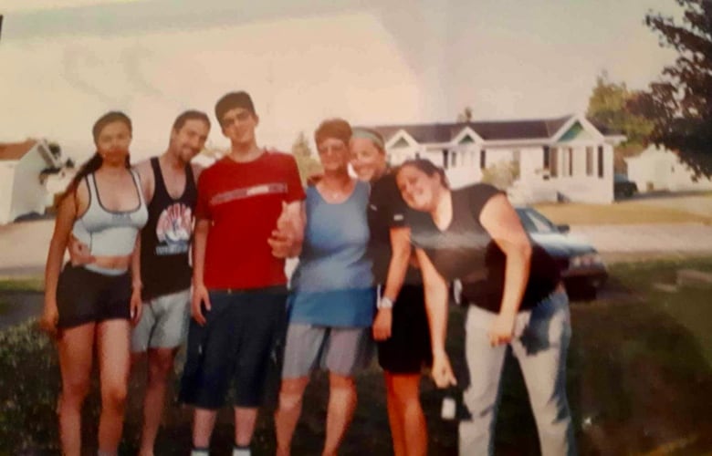 A printed photo showing a group of people standing arm-in-arm in a neighbourhood.