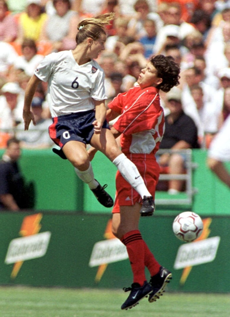 Two women soccer players battle for the ball.