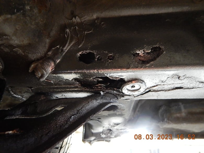 A close-up photo shows the corroded metal of part of the frame of a motor vehicle.