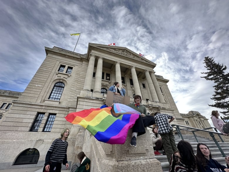 A youth waves a LGBTQ2+ flag on the steps of the provincial legislature in Regina, Sask. 