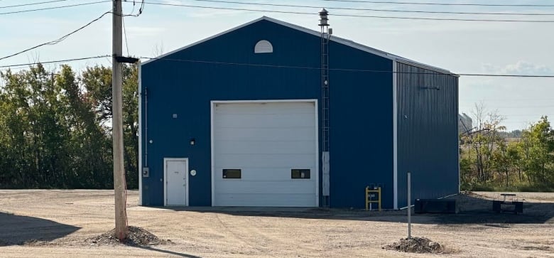 A plain blue building with two white doors, including a man-door and a garage door. 