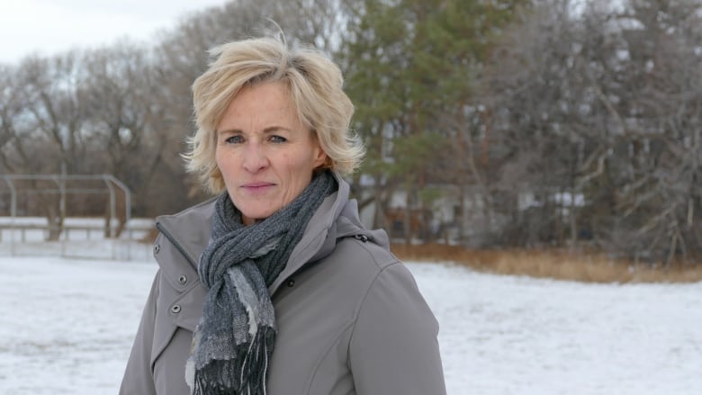 A white woman with short blonde hair poses for a picture in a snowy park.
