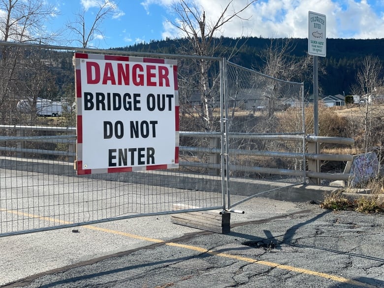 A bridge out sign and gate on a cracked road.