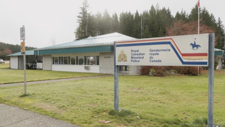 An exterior photo of a small office with a rectangular sign on the lawn that says Royal Canadian Mountain Police in both languages. 