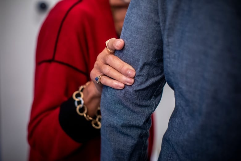 A woman's hand is seen clasping the arm of her son.