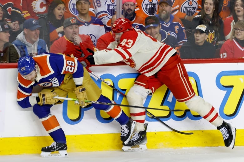 A professional hockey player hits an opponent while on the boards.