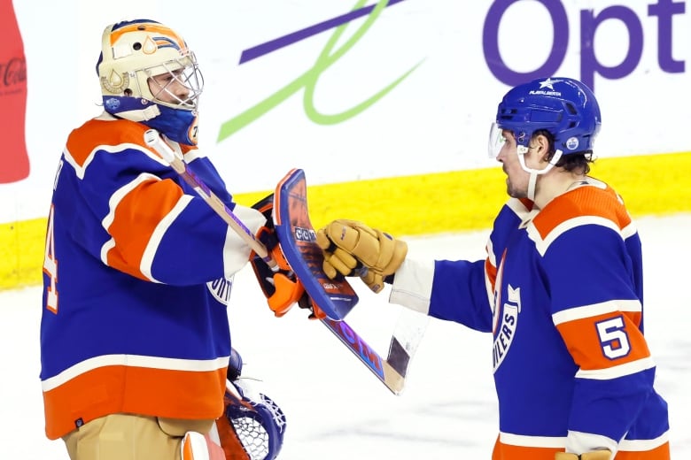 A hockey player fist bumps his goalie after winning a history-making game.