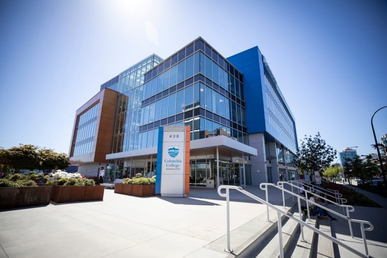 Vancouver's Columbia College, a square modern glass building, is shown in front of a blue sky.