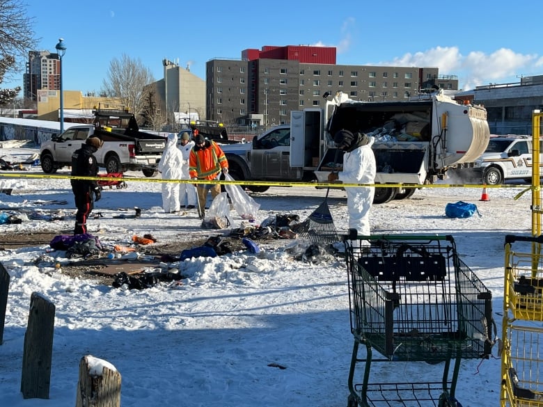 Staff in hazmat suits clean up the remains of a homeless encampment at 96th Street and 105th Avenue.