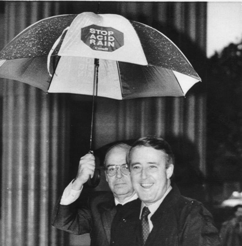 Prime Minister Brian Mulroney arrives in the rain at a Washington television studio Friday morning, May 5, 1989 where he appeared in an interview. Holding the Stop Acid Rain umbrella is Canadian Ambassador to the United States Derek Burney.