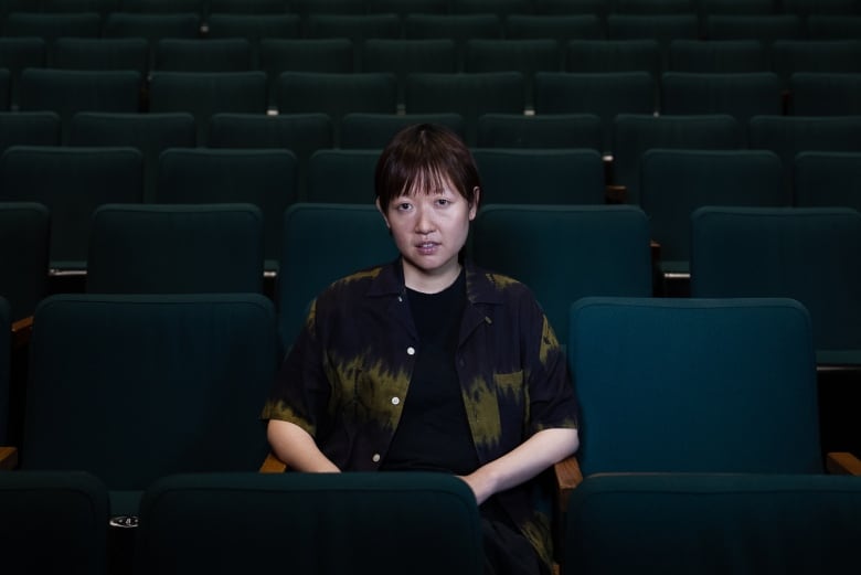 A woman sits alone in a theatre.