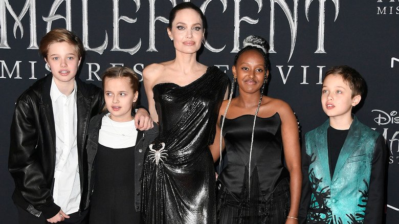 Zahara Jolie wearing a black dress and posing with her family at the Hollywood premiere of Maleficent: Mistress of Evil