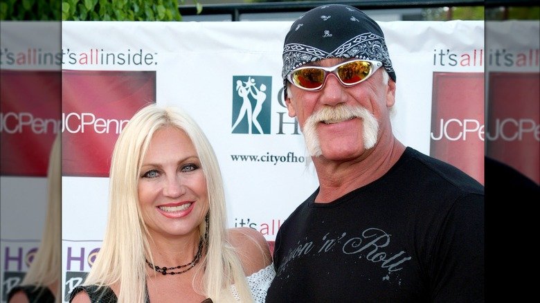 Hulk Hogan and Linda Hogan pose side to side and flash wide smiles.