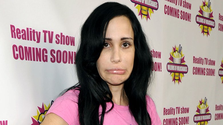 Natalie Suleman posing in front of a banner making a sad face