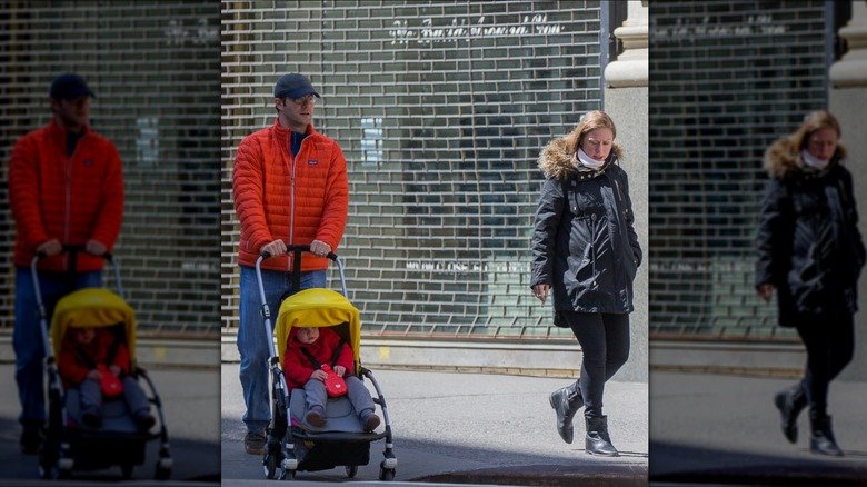 Marc Mezvinsky pushing stroller with baby inside as Chelsea Clinton walks next to them