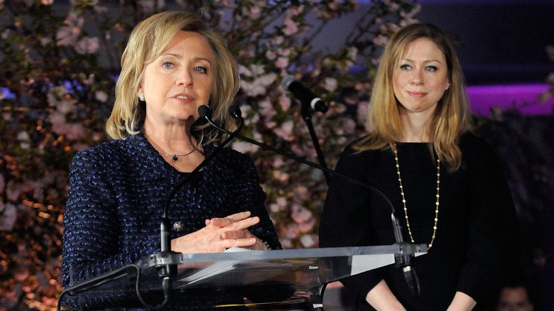 Hillary Clinton making speech at podium as Chelsea Clinton watches from the stage