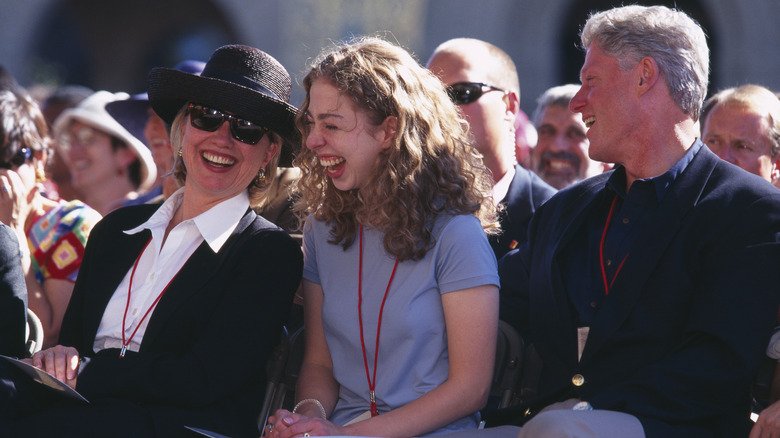 Hillary, Chelsea, and Bill Clinton sitting in audience laughing