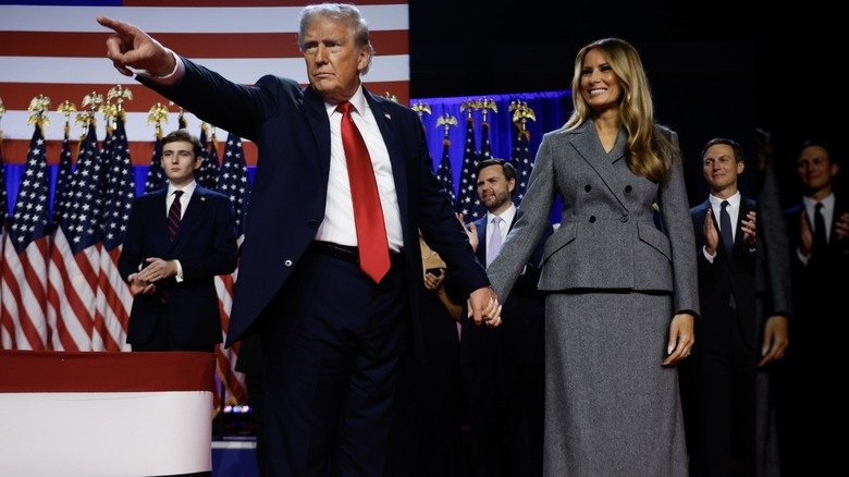Melania Trump smiling while holding Donald Trump's hand