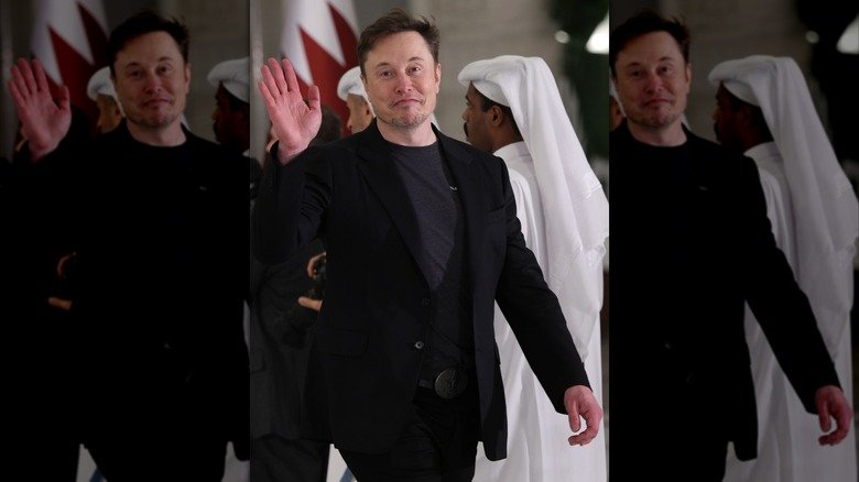 Elon Musk waves as he arrives at a Qatar state dinner.