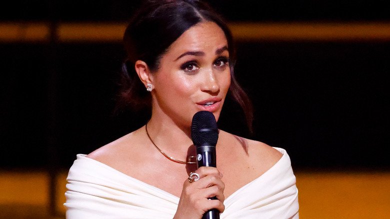 Meghan Markle holding a microphone while making a speech