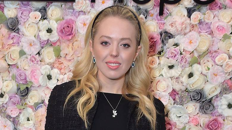Tiffany Trump posing in front of a backdrop of fresh flowers