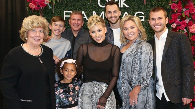The Chrisley family members all look at the camera and smile while standing close to each other.