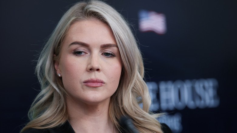 Karoline Leavitt glances down at a reporter speaking at a White House press briefing.