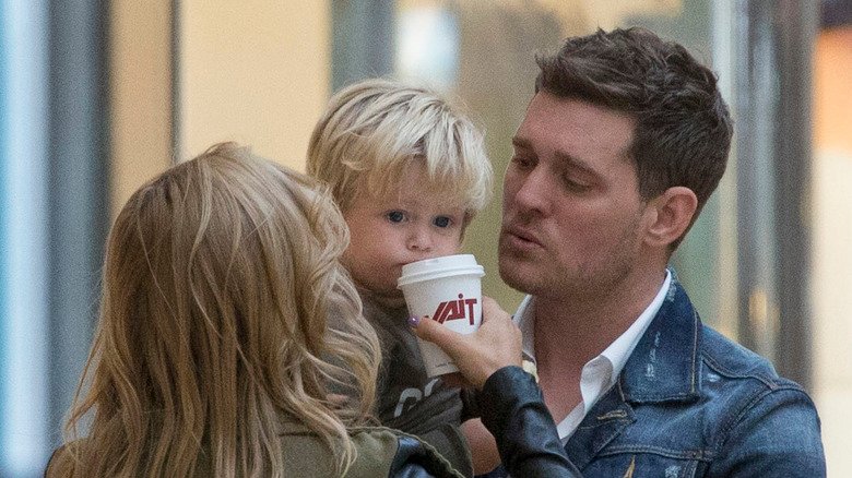 Michael Bublé holding his son Noah as his wife Luisana holds a cup to Noah's lips to drink