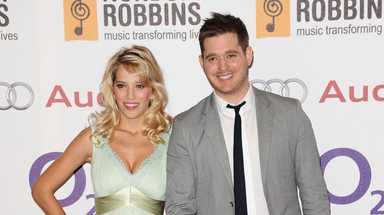 Luisana Lopilato wearing a mint green lace dress with a green satin belt and Michael Buble wearing a grey suit, white collard shirt, and black tie