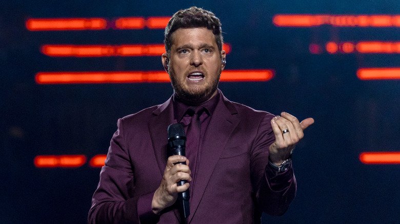 Michael Bublé wearing a purple suit, purple shirt and purple tie while holding a microphone