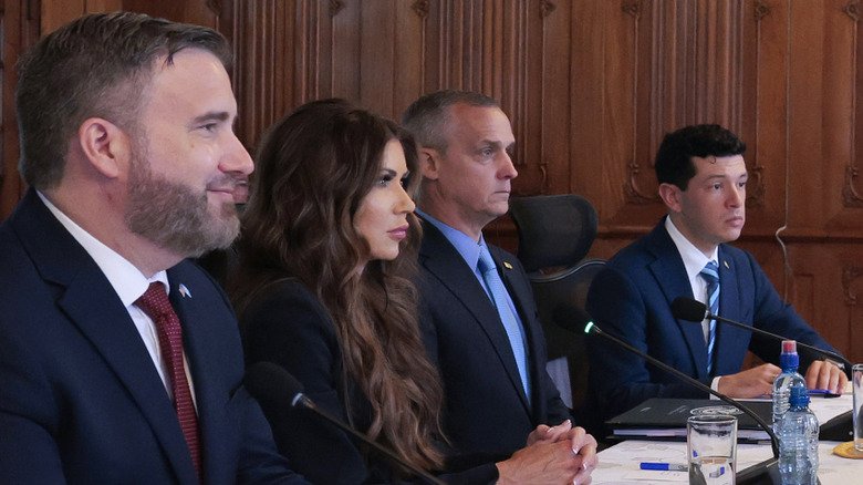 Corey Lewandowski and Kristi Noem, sitting side by side at a meeting in 2025