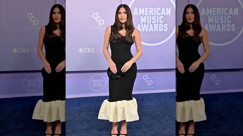 The 2026 American Music Awards Was A Fashion 141 Jessi Draper wearing an ankle-length black gown with a large off-white ruffle on the bottom at the 2026 AMAs.