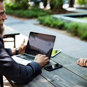 Two business researchers discussing charts on a laptop