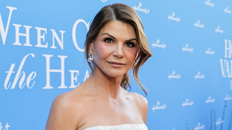 Lori Loughlin looking at the camera while posing at an event in front of a light-blue background