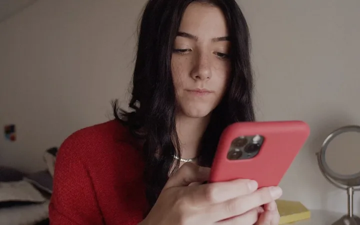 Charli D’Amelio holding a smartphone during an interview