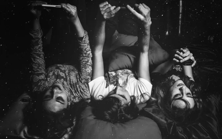 People lying in bed while using smartphones at night, illustrating late-night screen use