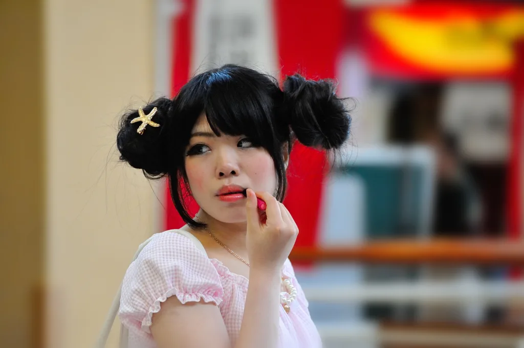 Woman applying red lipstick illustrating the bold lip trend for fall 2026