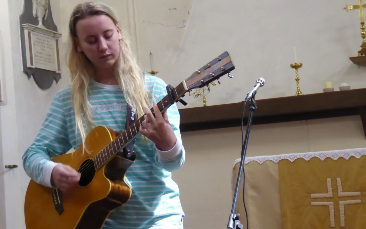 Emma Chamberlain playing guitar during a live performance at Lostfest in 2017