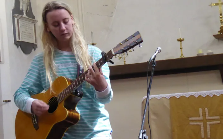 Emma Chamberlain playing guitar during a live performance at Lostfest in 2017