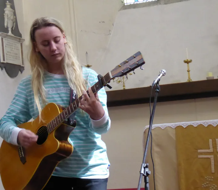 Emma Chamberlain playing guitar during a live performance at Lostfest in 2017