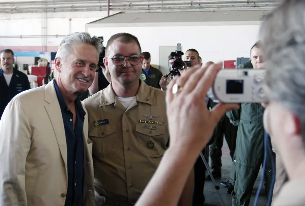 Michael Douglas posing with a U.S. Navy sailor during a 2004 visit to Naval Air Station Sigonella