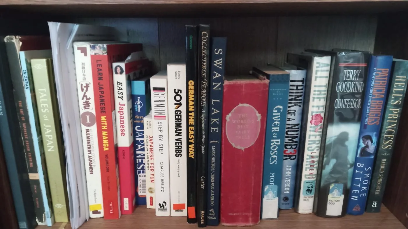 Open the featured image for Organising Your Bookshelf: A Practical Guide to Book Care A row of fiction and language books on a wooden bookshelf
