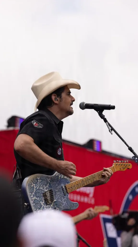 Brad Paisley singing into a microphone while playing a patterned guitar